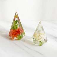 Two teardrop-shaped resin ring holders with embedded flowers on a white background