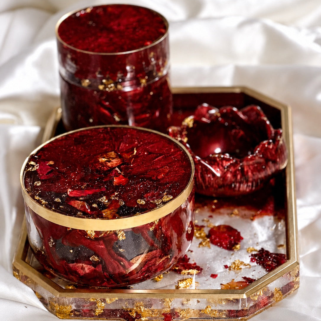 Three red resin keepsakes filled with dried flowers and gold leaf, arranged on a gold-trimmed octagonal tray with a white satin background.